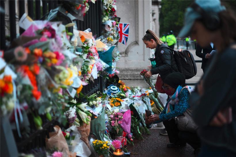 Menschen legen am Freitag, einen Tag nach dem Tod von Königin Elisabeth II., Blumen vor dem Buckingham-Palast in London ab
