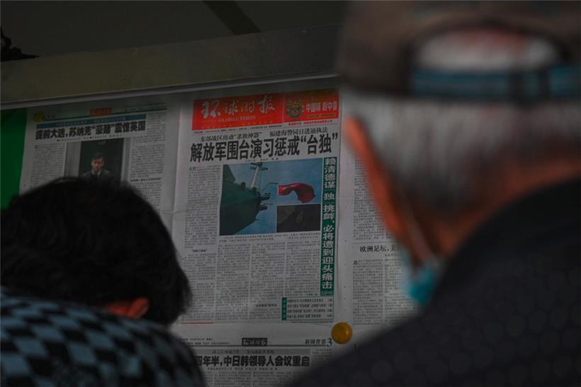 Menschen lesen in Peking eine chinesische Zeitung mit Berichten über chinesische Militärübungen um Taiwan
