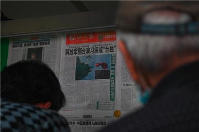 Menschen lesen in Peking eine chinesische Zeitung mit Berichten über chinesische Militärübungen um Taiwan
