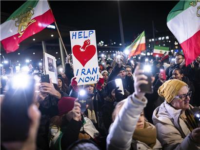 Menschen bei Solidaritätsdemonstration für Demonstranten im Iran mit Transparenten und Fahnen auf der Straße