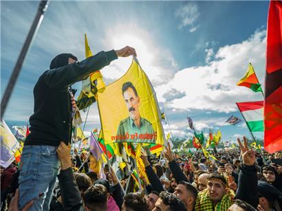 Menschen nehmen im März an der zentralen Feier in Frankfurt zum kurdischen Neujahrsfest „Newroz“ teil und schwenken dabei Fahnen
