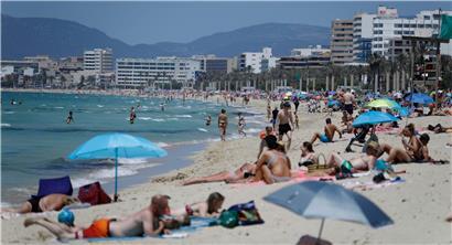 Menschen sonnen sich am Strand von Arenal: Die Tourismusbranche sieht ihr Sommergeschäft bedroht
