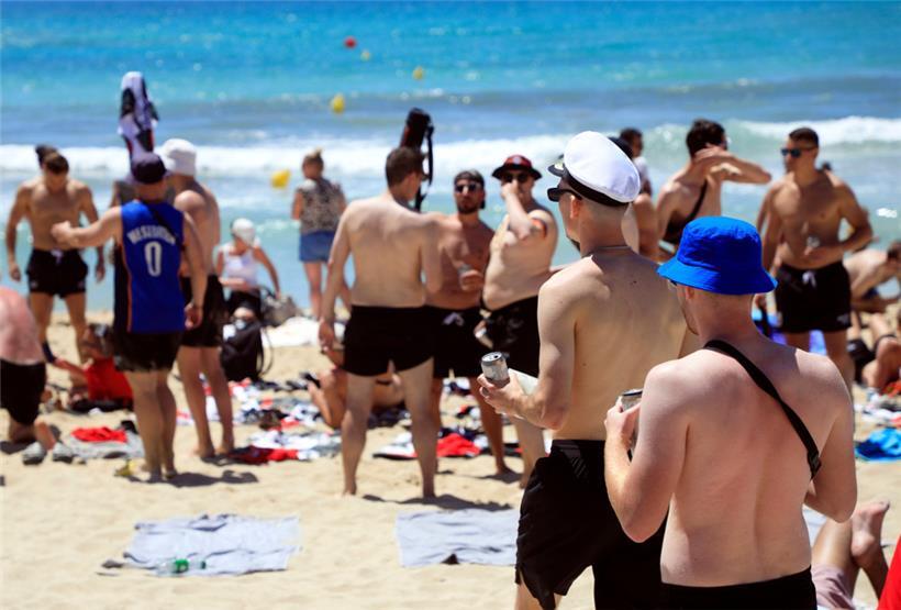 Menschen sonnen sich vor dem Pfingstwochenende am Strand von Arenal auf Mallorca
