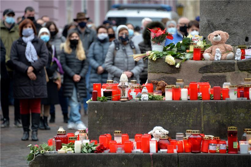 Menschen stehen bei einer Schweigeminute zum Gedenken der Opfer nach der Amokfahrt von Trier mit Toten und Verletzten in der Innenstadt. In der ganzen Stadt läuten die Kirchenglocken.
