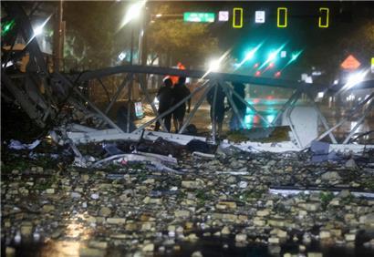 Menschen stehen hinter einem umgestürzten Kran an der 1st Avenue South in der Nähe der Büros der Tampa Bay Times, als Hurrikan „Milton“ auf Land trifft
