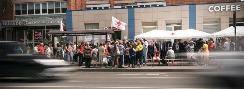 Menschen stehen um Hilfe an am Stand des Roten Kreuzes in Kursk
