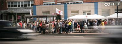 Menschen stehen um Hilfe an am Stand des Roten Kreuzes in Kursk
