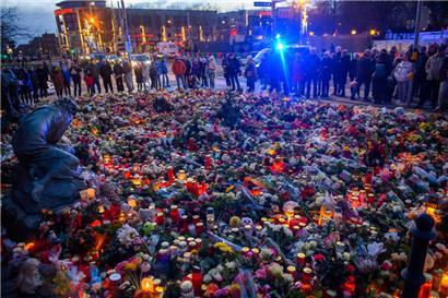 Menschen stehen vor der Johanniskirche an dem ein Gedenkort eingerichtet wurde und an dem vor dem Portal Blumen und Kerzen niedergelegt wurden

