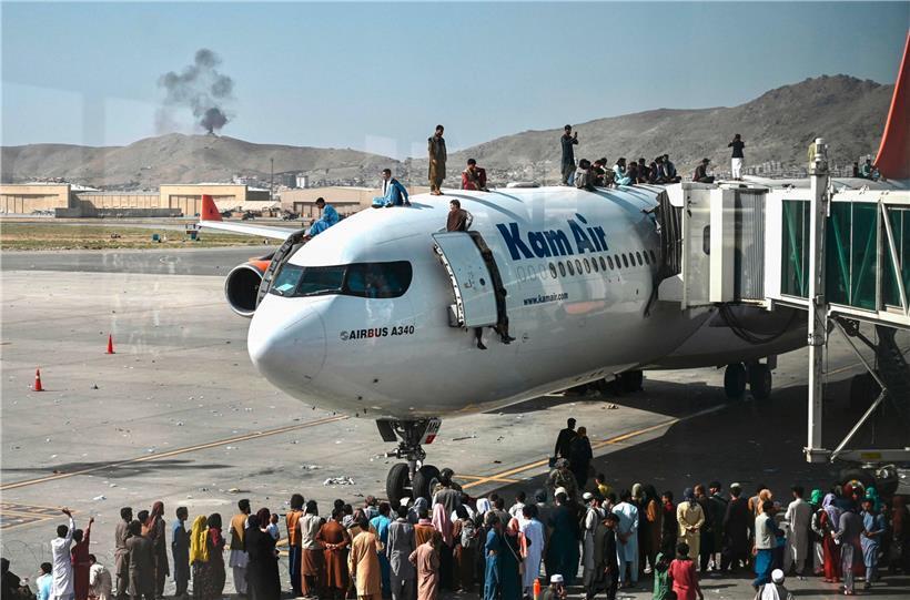 Menschen steigen am Flughafen in Kabul auf das Dach eines Flugzeugs
