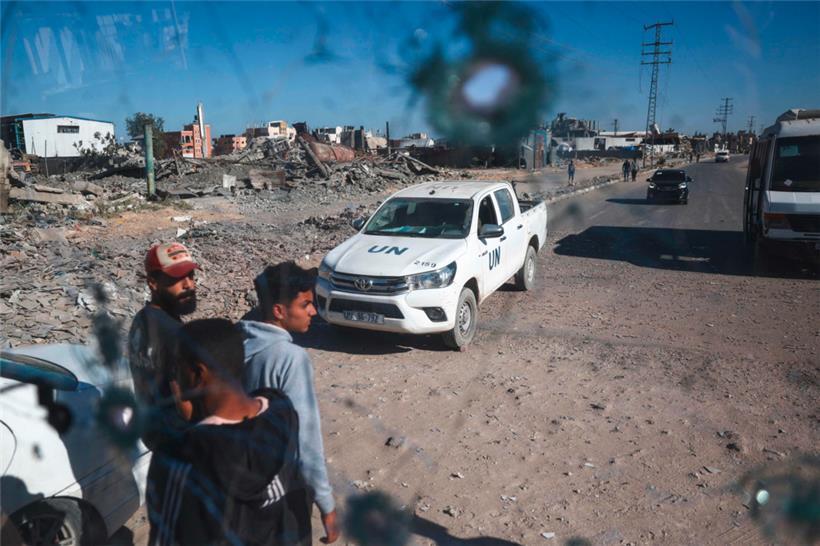 Menschen und ein Fahrzeug des Hilfswerks der Vereinten Nationen für Palästinaflüchtlinge (UNRWA) durch die mit Schrapnellen durchsetzte Windschutzscheibe eines Busses
