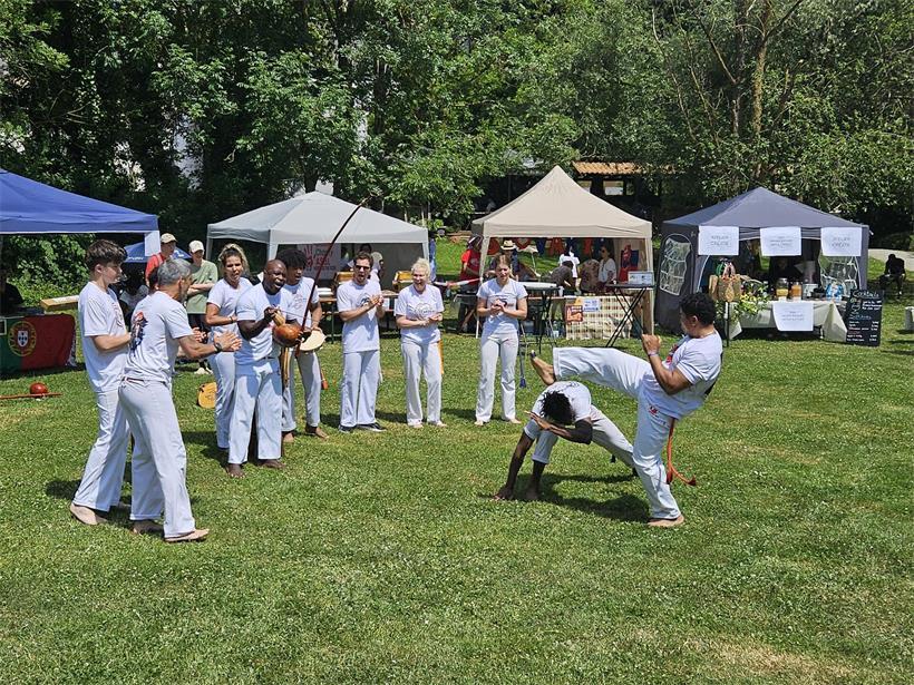 „Das Zusammenleben ist unsere Stärke“ Mestre Pelezinho und Schüler bei dynamischer Capoeira-Vorführung im Freien mit traditionellen Kostümen
