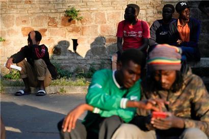Migranten warten in der Nähe eines Bahnhofs in Rom auf einen Bus nach Marseille
