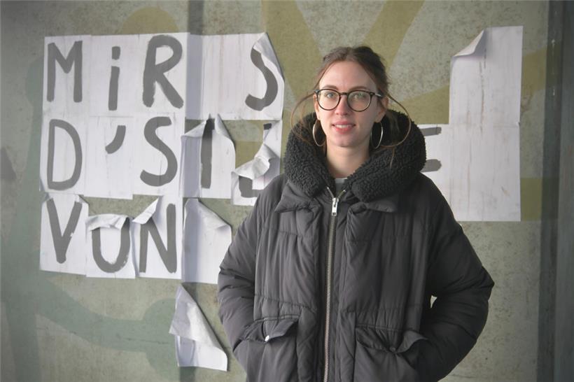 Milena Steinmetzer, eine der Organisatorinnen des Frauenstreiks, vor einer zerrissen feministischen Collage, die einst besagte:  „Mir sinn d’Stëmme vun deenen, déi dir verstommt hutt.“
