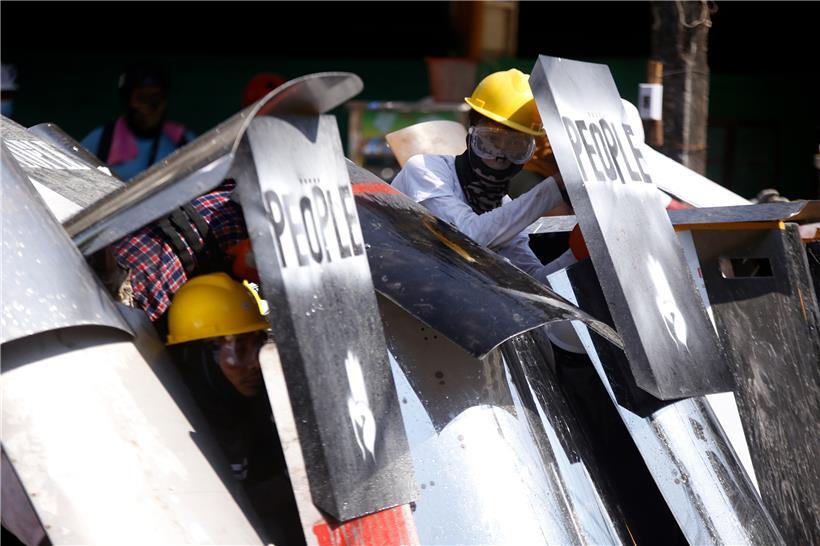 Mit Schildern versuchen die Demonstranten sich vor den Schüssen der Schergen des Militärregimes zu schützen
