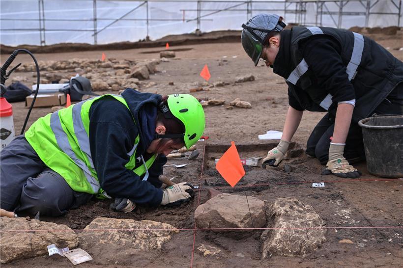 Archäologe mit feinem Grabungswerkzeug legt geduldig historische Artefakte bei Ausgrabung frei