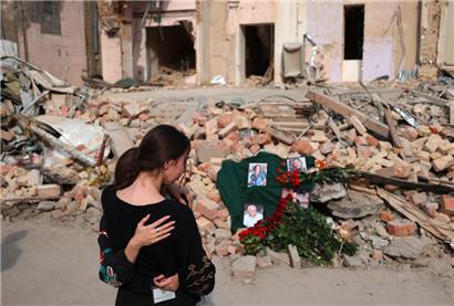 Mitarbeiterinnen eines Kinderkrankenhauses, das jüngst von der russischen Armee angegriffen wurde, trauern während einer Feier um getötete Kolleg*innen
