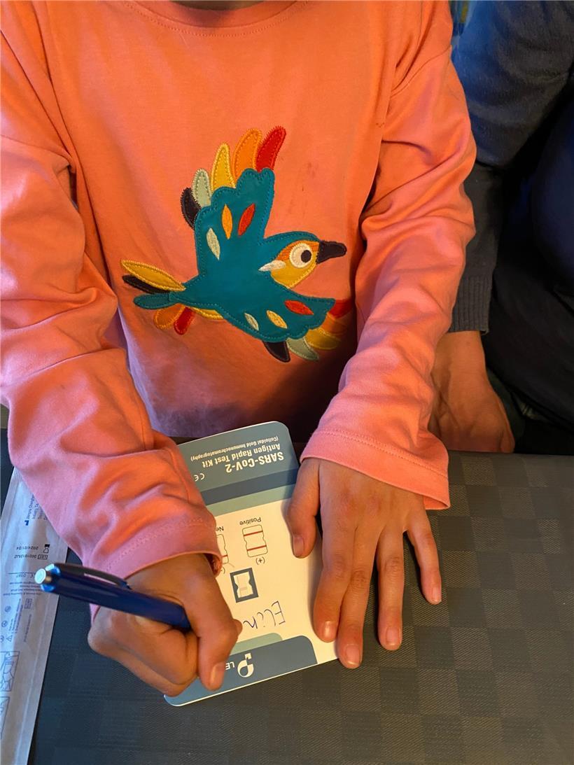 Nach dem Auspacken des Testkits schreibt die Schülerin ihren Namen auf die Karte des Schnelltests
