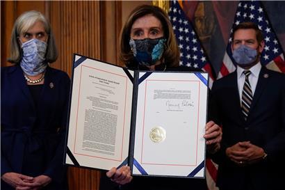 Nancy Pelosi (M), Sprecherin des Repräsentantenhauses, hält das von ihr unterzeichnete Dokument für das Amtsenthebungsverfahren gegen Trump
