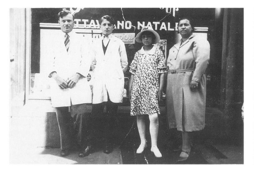Natale Ottaviano, son apprenti Guerrino Pasquini, sa fille Gina et son épouse Santina Dall’Agnol devant le salon de coiffure de la rue des Boers vers 1939
