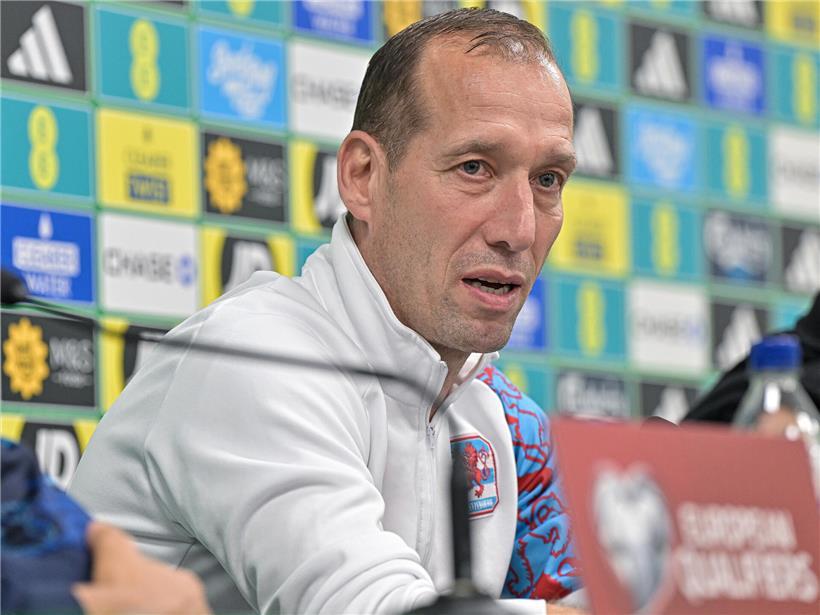 Nationaltrainer Jeff Strasser im Anzug während einer Pressekonferenz zum Fußballspiel