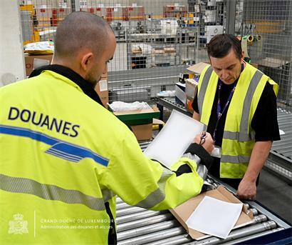 E-Commerce Paket mit Weltkugel und Zollsymbol, Hinweis auf ab 1. Juli neue Versandkosten aus Fernost