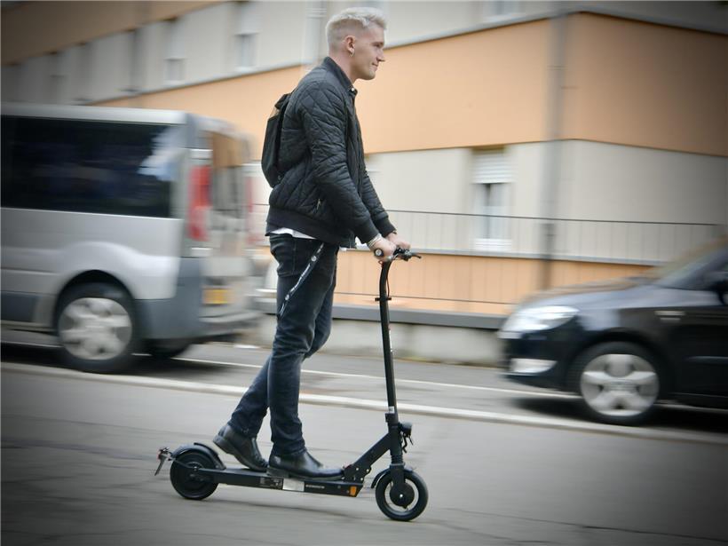 Zweiradfahrer auf Straße mit ablehnenden Fußgängern und Autos im urbanen Verkehrsstress