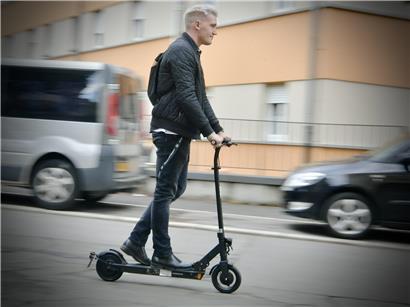Zweiradfahrer auf Straße mit ablehnenden Fußgängern und Autos im urbanen Verkehrsstress