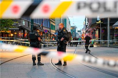 Norwegische Polizeibeamte stehen am Samstag in den Straßen des Osloer Stadtzentrums zwischen Absperrbändern Wache, nachdem vor einem Pub Schüsse abgefeuert worden waren
