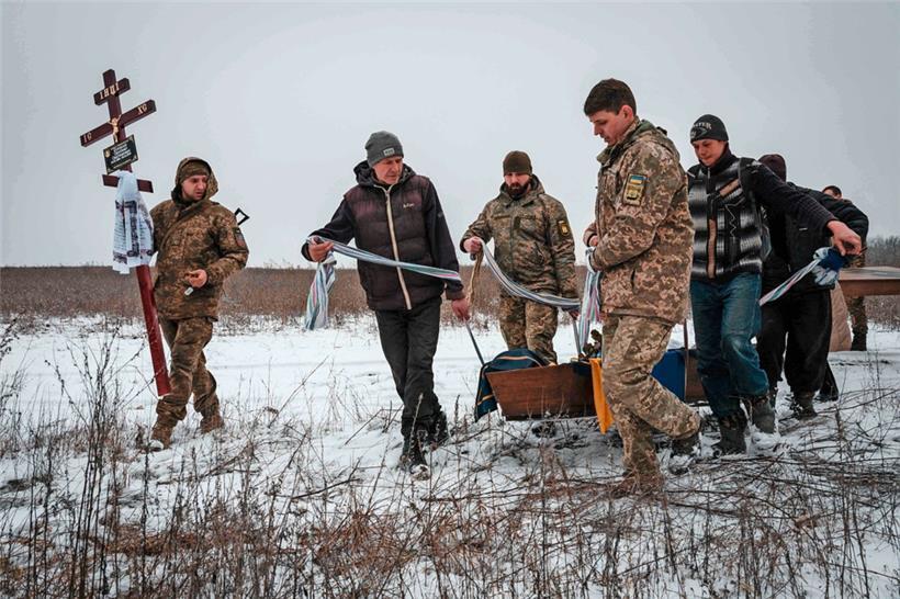Oleksiy Storozh (28) trägt ein Kreuz, das am Grab seines besten Freundes Oleksandr Korovniy (28) stehen soll, der bei den Kämpfen um Bachmut getötet und gestern auf einem Friedhof bei Sloviansk begraben wurde
