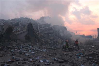 Palästinenser begutachten die Schäden vor dem Al-Watan-Turm in Gaza-Stadt, der am frühen Morgen des 8. Oktober 2023 durch einen israelischen Luftangriff zerstört wurde
