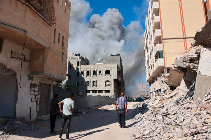 Palästinenser beobachten, wie Rauch aus einem Gebäude aufsteigt, das von einem israelischen Angriff getroffen wurde
