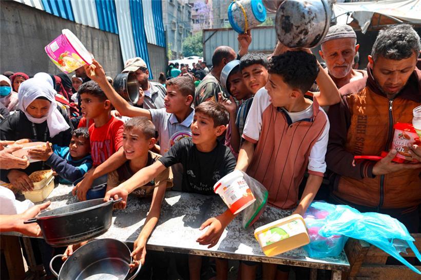 Palästinenser drängeln sich vor einer Verteilerstelle im Flüchtlingslager Nuseirat im zentralen Gazastreifen, um eine warme Mahlzeit zu erhalten
