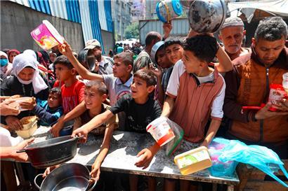 Palästinenser drängeln sich vor einer Verteilerstelle im Flüchtlingslager Nuseirat im zentralen Gazastreifen, um eine warme Mahlzeit zu erhalten

