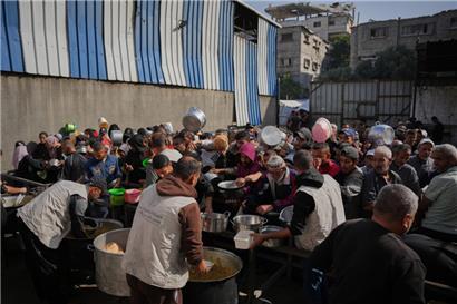 Palästinenser drängen sich um gespendete Lebensmittel in einer Gemeinschaftsküche in Nuseirat im zentralen Gazastreifen
