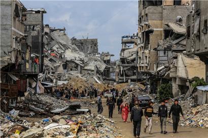 Palästinenser gehen durch die zerstörten Gebäude, nachdem sich die israelischen Streitkräfte im Rahmen der Waffenruhe mit der Hamas zurückgezogen haben
