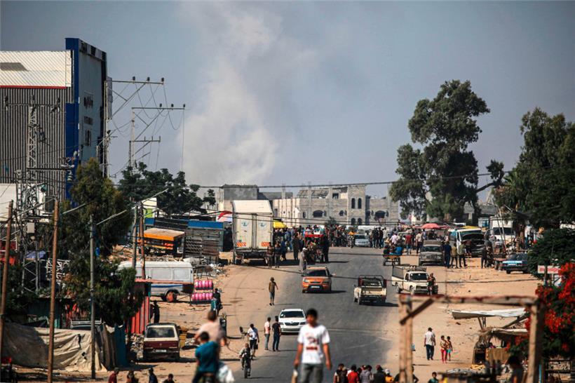 Palästinenser gehen ihrer täglichen Arbeit nach, während nach dem israelischen Bombardement der Stadt Rafah im südlichen Gazastreifen Rauch aufsteigt
