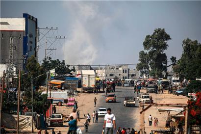 Palästinenser gehen ihrer täglichen Arbeit nach, während nach dem israelischen Bombardement der Stadt Rafah im südlichen Gazastreifen Rauch aufsteigt
