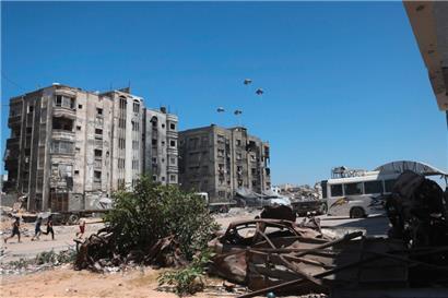 Palästinenser rennen zu Hilfspaletten, während diese nach dem Abwurf aus einem Militärflugzeug nahe Jabalia im nördlichen Gazastreifen am 20. August 2025 herabsegeln
