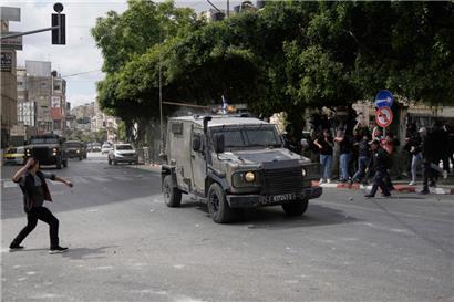 Palästinenser stoßen nach einer Razzia der Armee in der Stadt Nablus im Westjordanland mit israelischen Sicherheitskräften zusammen und werfen Steine auf ein Auto
