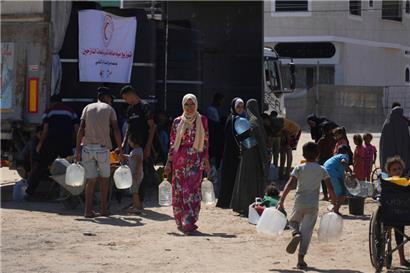 Palästinenser tragen Wasserbehälter in einem Lager für Vertriebene in Deir al-Balah
