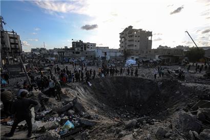 Palästinenser versammeln sich um einen großen Krater nach einem israelischen Angriff auf eine Metallwerkstatt im Stadtteil Zaytun in Gaza-Stadt
