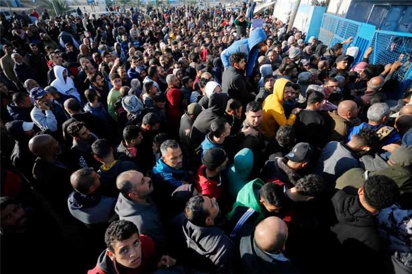 Palästinensische Gebiete, Dair El-Balah: Palästinenser stehen an, um Mehl zu erhalten, das von der UN-Agentur für palästinensische Flüchtlinge (UNRWA) an die Bewohner des Gazastreifens verteilt wird
