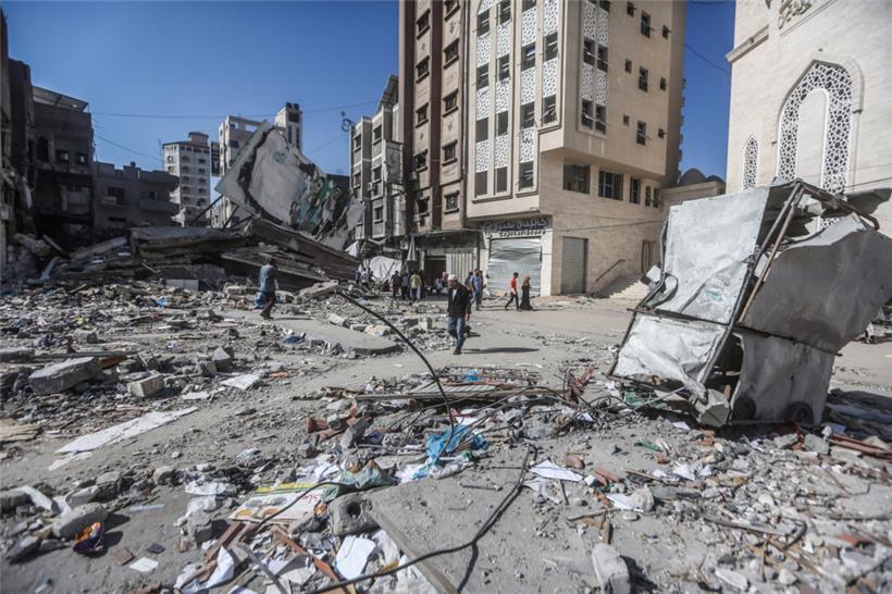 Palästinensische Gebiete, Khan Yunis, südlicher Gaza-Streifen: Palästinenser gehen an den Überresten von Gebäuden vorbei, die bei israelischen Luftangriffen zerstört wurden. Während Hunderttausende Palästinenser im Süden des Gazastreifens Schutz vor der erwarteten israelischen Bodenoffensive suchen, bombardiert Israels Luftwaffe nach eigenen Angaben weiter Hamas-Ziele. 
