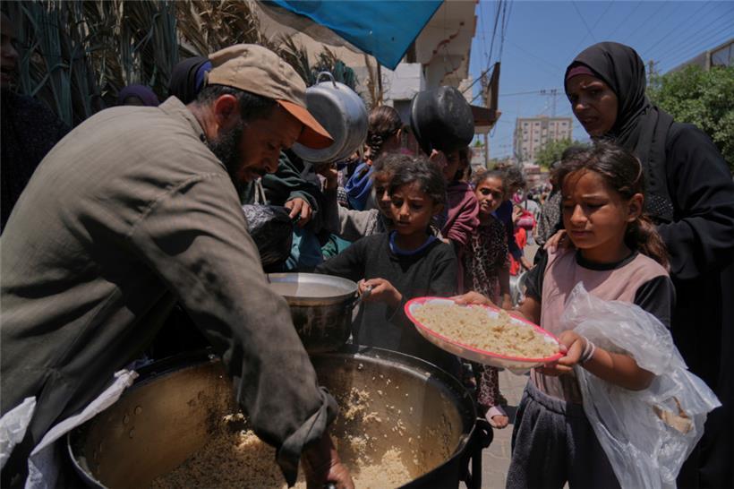 Palästinensische Kinder erhalten bei einer Lebensmittelverteilungsküche Essen
