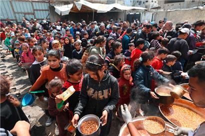 Palästinensische Kinder stehen am 12. April in einem Flüchtlingslager im Zentrum des Gazastreifens für eine Suppe an. Wegen der Lebensmittel-Blockade der israelischen Regierung werden sie in diesen Tagen auch diese Mahlzeit nicht mehr erhalten.
