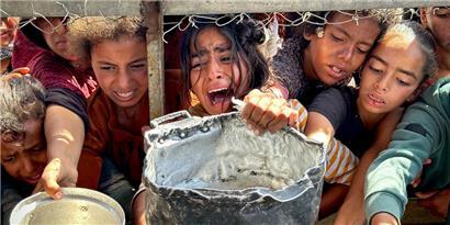 Palästinensische Kinder versuchen im Gebiet Al-Mawasi im Gazastreifen, mit ihren Töpfen Nahrungsmittel zu bekommen, die von Wohltätigkeitsorganisationen verteilt werden
