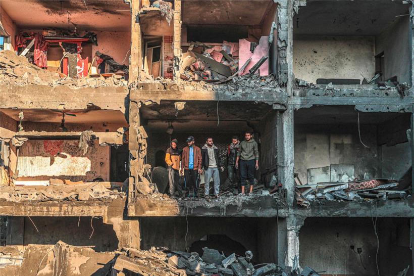 Palästinensische Männer stehen in Rafah in den Ruinen eines durch israelisches Bombardement zerstörten Wohnhauses
