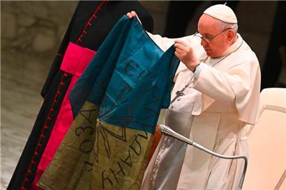 Papst Franziskus hält während der wöchentlichen Generalaudienz am 6. April 2022 in der Paul-VI-Halle im Vatikan eine ukrainische Flagge, die aus der Stadt Butscha stammt
