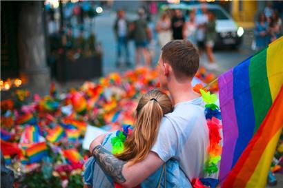 People with a rainbow flag lay flowers at a memorial at the crime scene on June 25, 2022, in the aftermath of a shooting outside pubs and nightclubs in central Oslo killing two people injuring 21. (Photo by Martin Solhaug Standal / NTB / AFP) / Norway OUT
