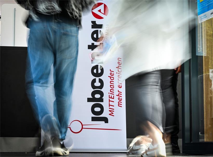 Personen gehen am Logo vom Jobcenter Berlin-Mitte bei einer Jobmesse vorbei
